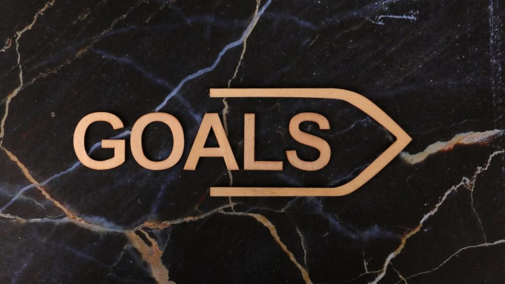 Inspiring image of a wooden 'GOALS' sign on a dark marble surface, symbolizing ambition.